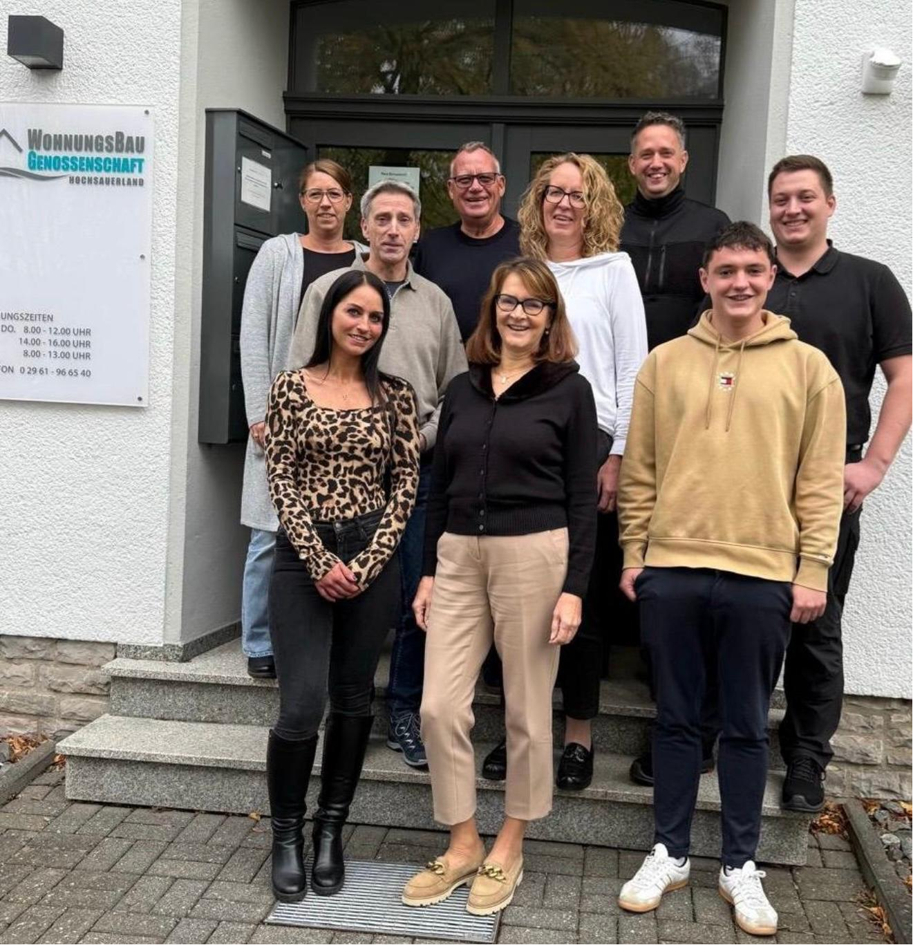 Mitarbeiterinnen und Mitarbeiter der Wohnungsbaugenossenschaft Hochsauerland vor dem Bürogebäude